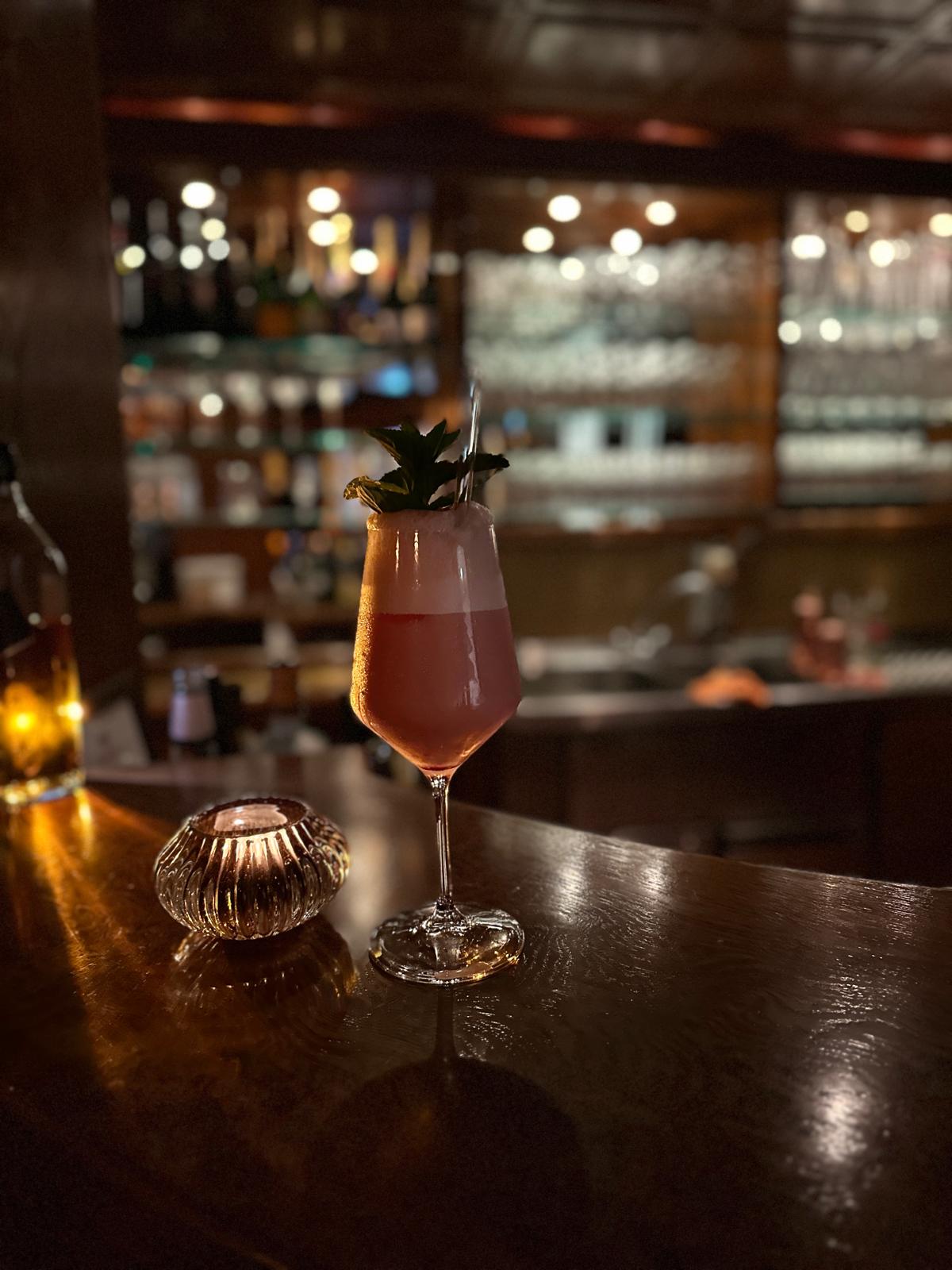 Cocktailglas bei Kerzenlicht vor der Bar